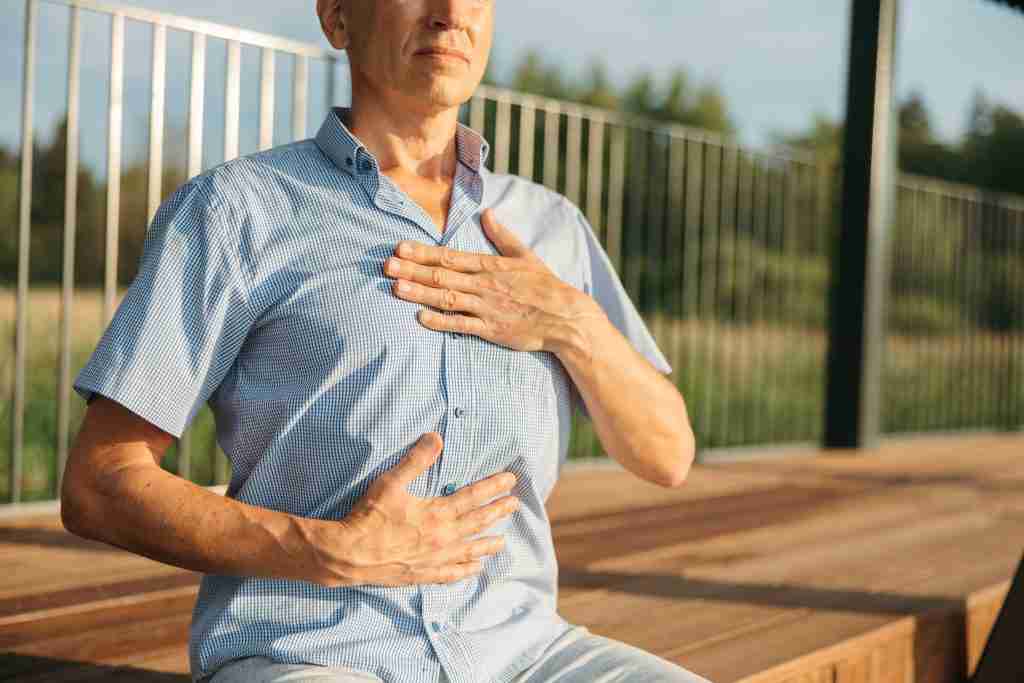 Uomo seduto esegue il test mano-torace mano-addome per valutare il pattern respiratorio diaframmatico