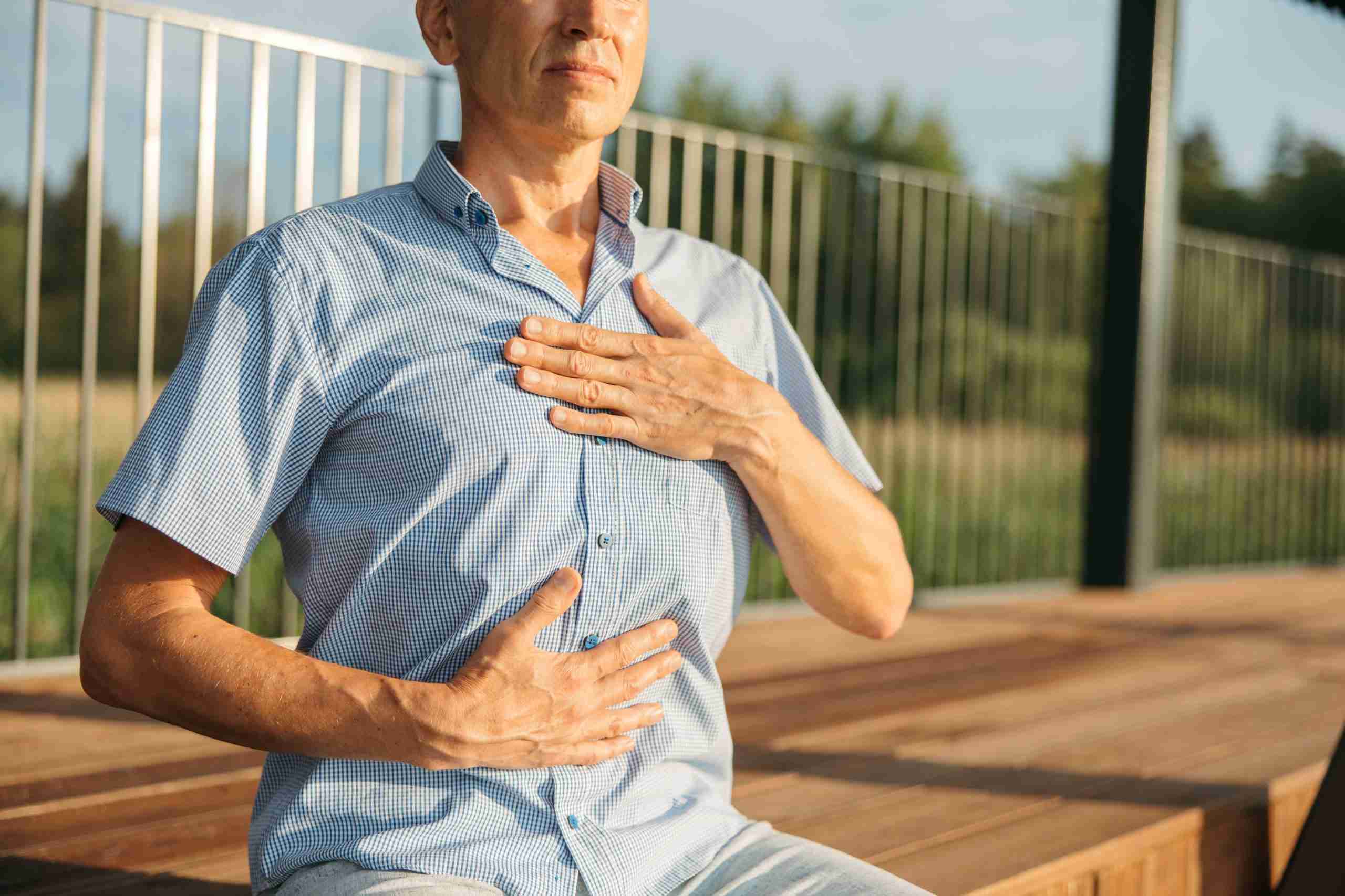 Uomo seduto esegue il test mano-torace mano-addome per valutare il pattern respiratorio diaframmatico